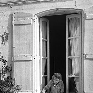 Old lady leans out of her house window - St Martin, France